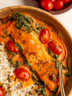 Wooden bowl of roasted red pepper salmon with vegetables and brown rice.