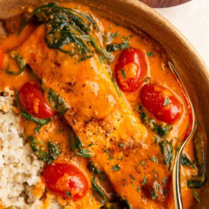 Wooden bowl of roasted red pepper salmon with vegetables and brown rice.