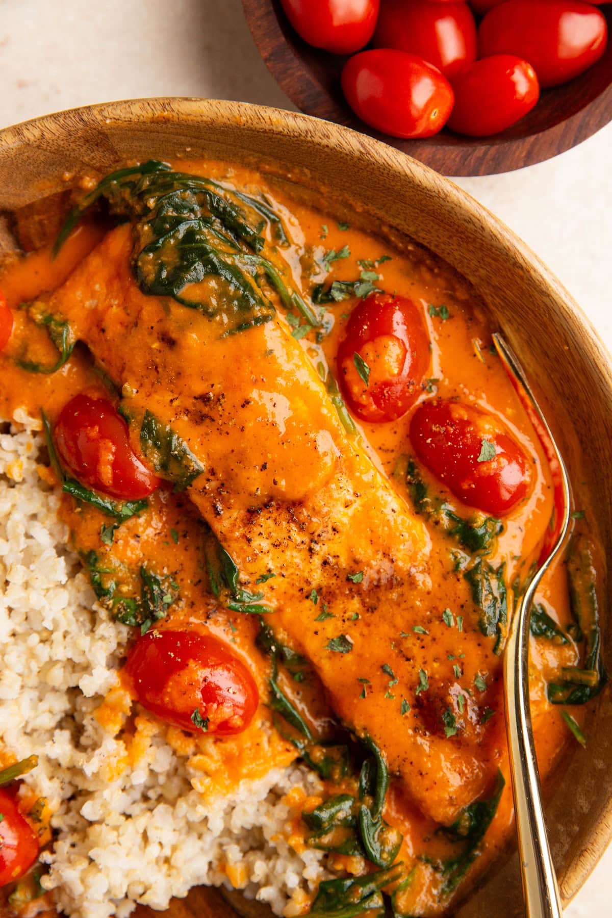 Wooden bowl of roasted red pepper salmon with vegetables and brown rice.