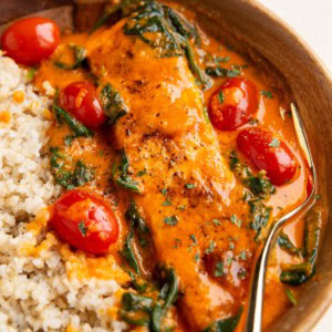 Wood bowl with crispy red pepper salmon and brown rice inside, ready to eat.