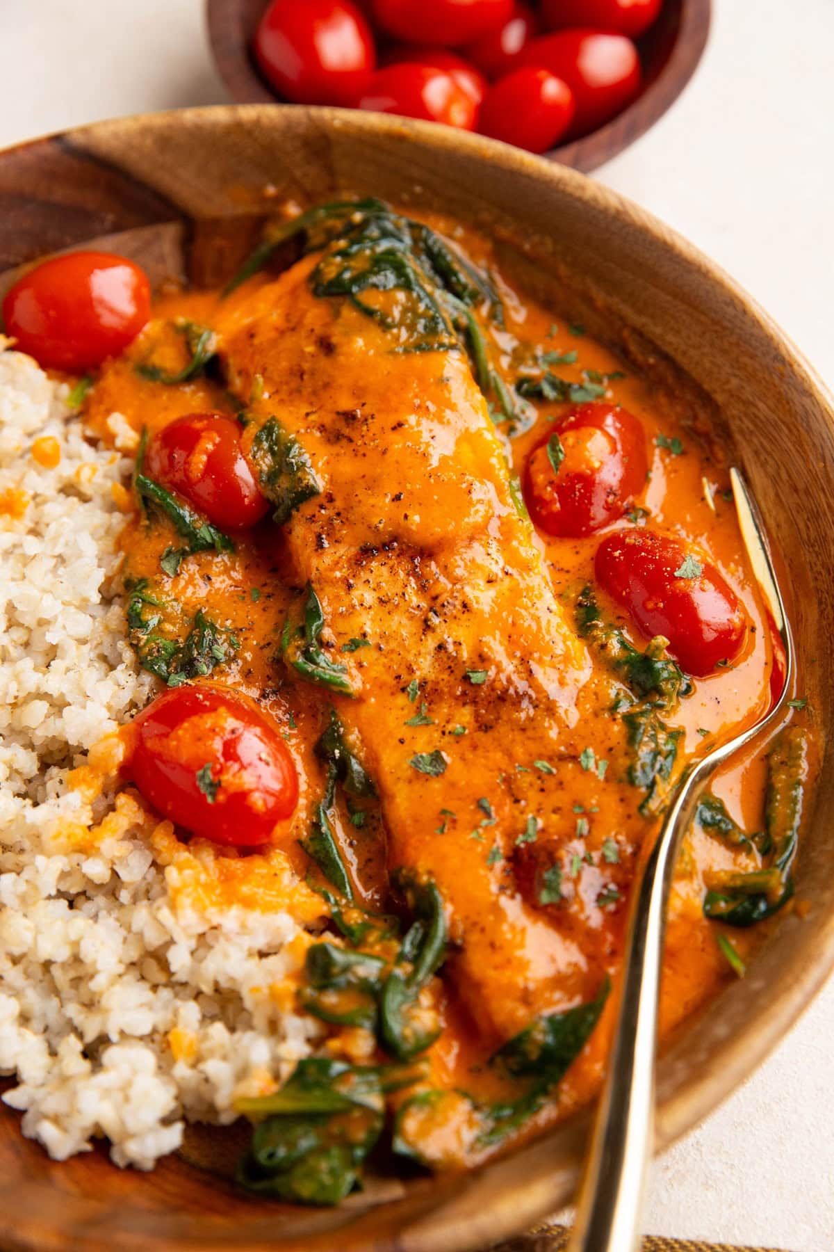 Wood bowl with crispy red pepper salmon and brown rice inside, ready to eat.