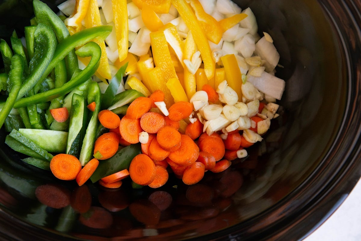 Bell peppers, carrots, onions and garlic in a crock pot for chicken cacciatore.