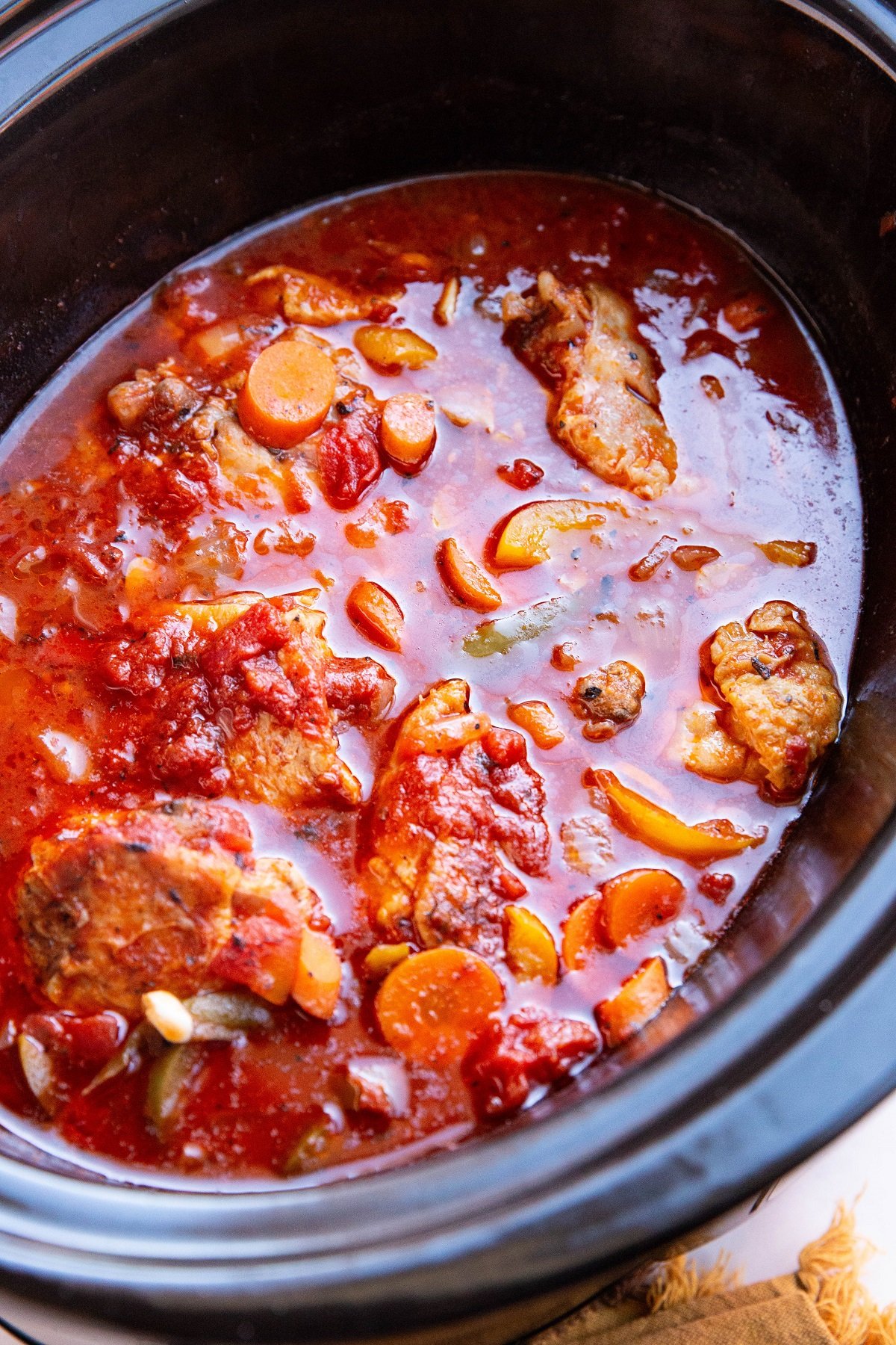 Crock pot full of cooked chicken cacciatore, ready to serve.