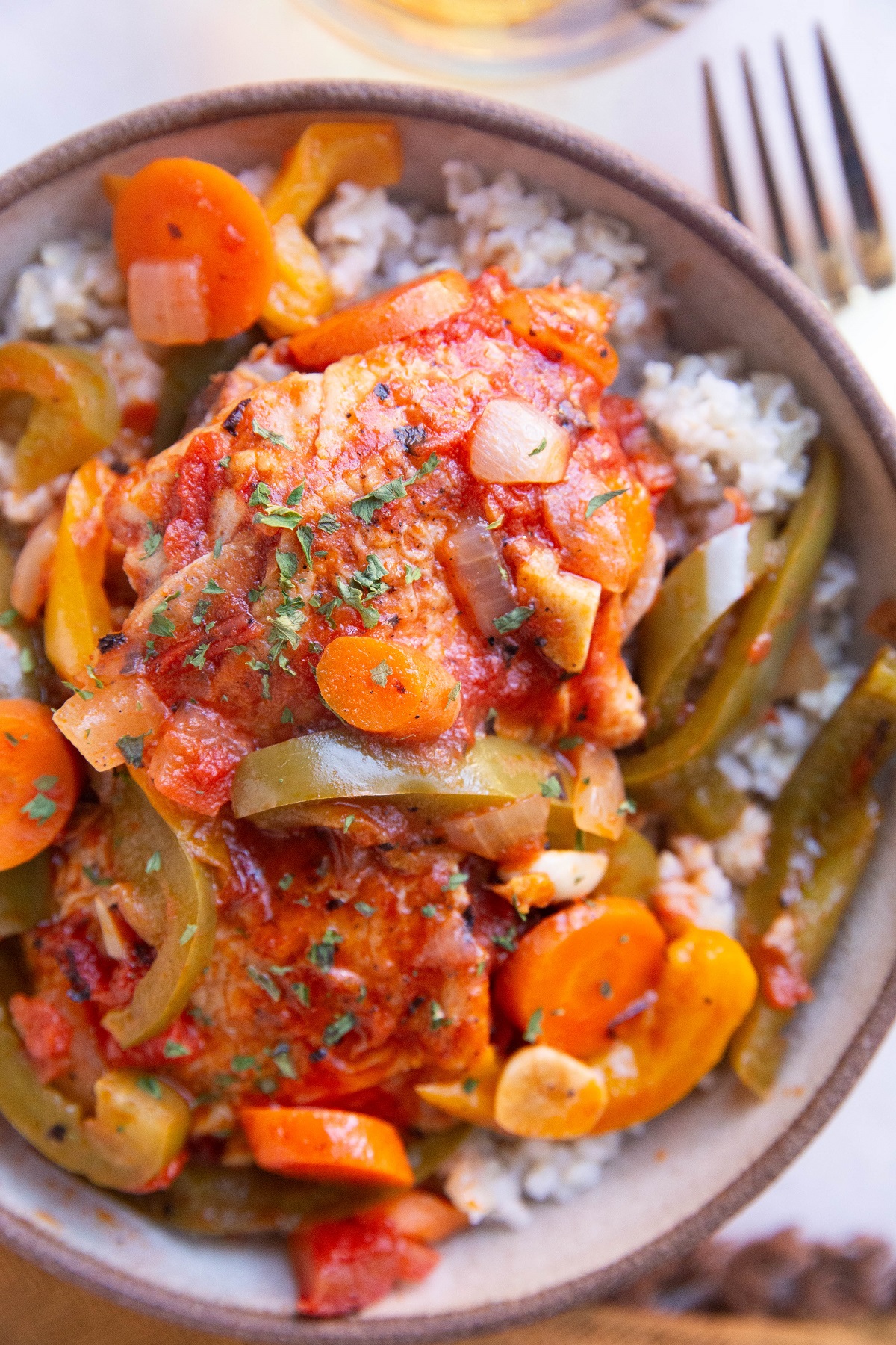 Chicken cacciatore in a bowl over brown rice, ready to eat.