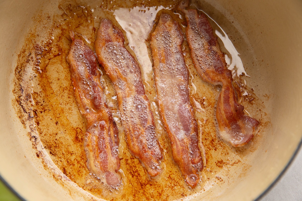 Bacon cooking in a large Dutch oven to crispy goodness.