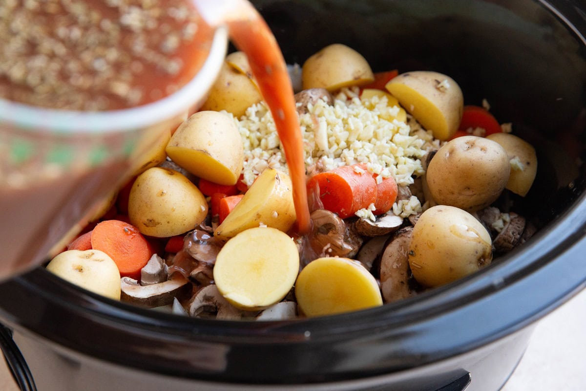 Pouring broth and wine mixture into the crock pot.