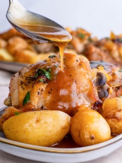 Spoon drizzling sauce over chicken and potatoes.