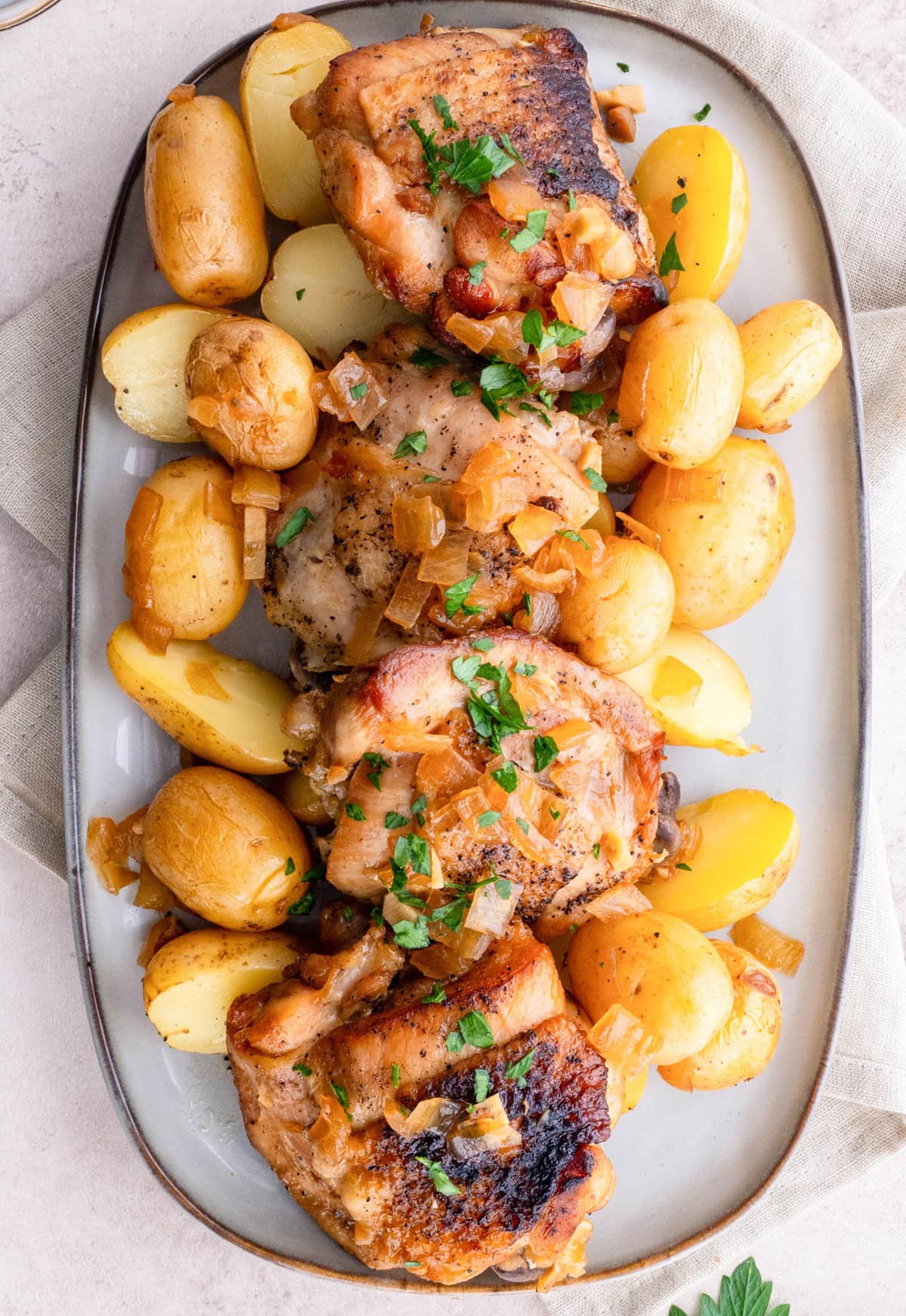 Platter of chicken and potatoes with a napkin, sprinkled with parsley.