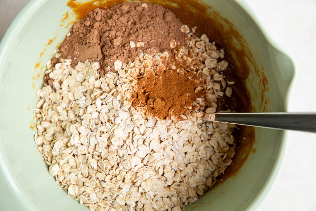 Wet ingredients in a mixing bowl with dry ingredients added on top, ready to mix.