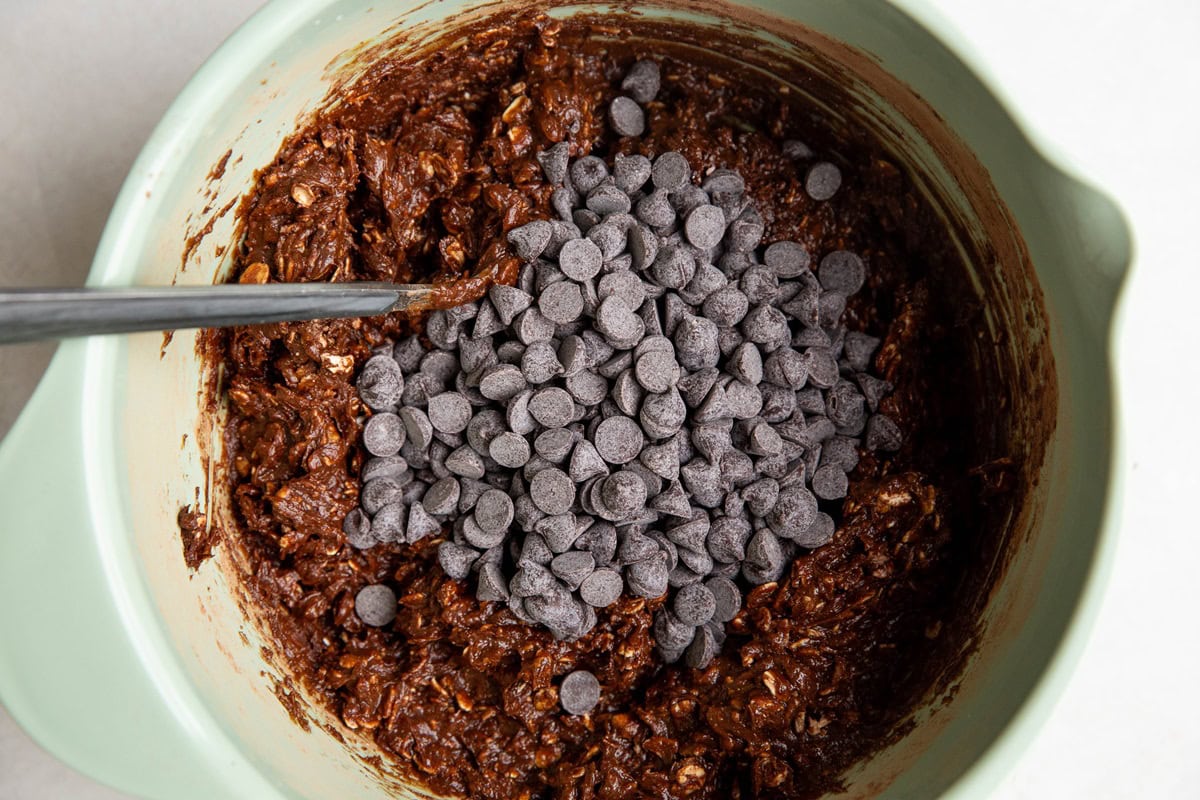 Double chocolate peanut butter bar dough in a mixing bowl with chocolate chips on top, ready to be mixed in.