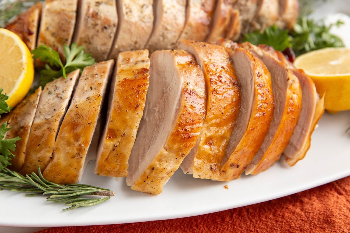 Sliced turkey breasts on a white serving platter.