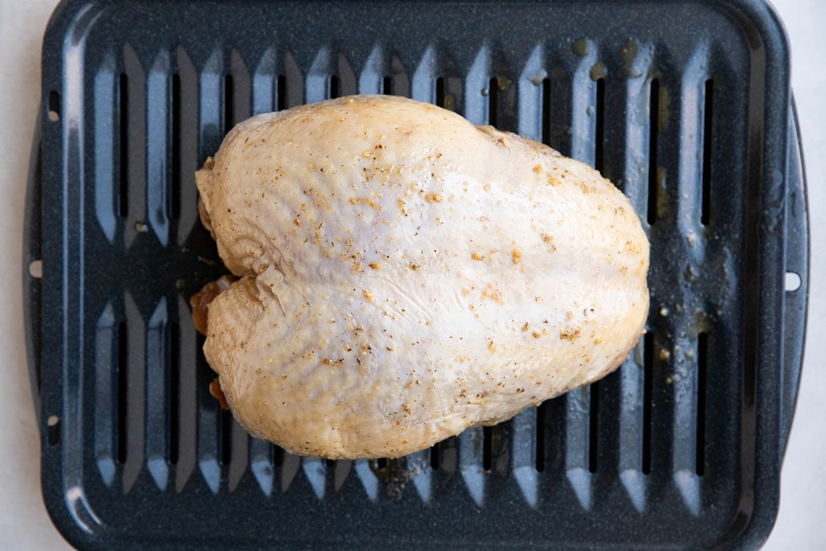 Marinated turkey breast on a roasting pan.