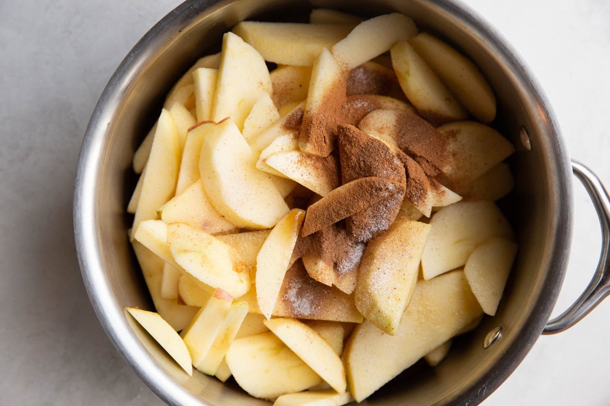 Apples in a saucepan with cinnamon, pure maple syrup, and sea salt.