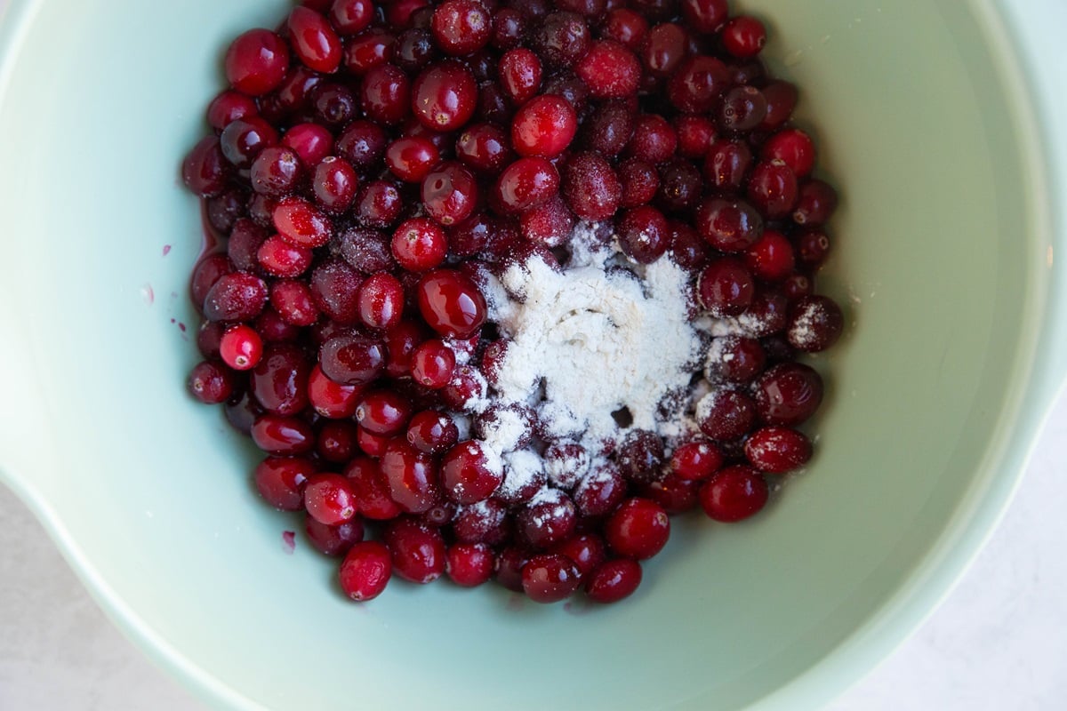 Cranberries in a mixing bowl with flour and pure maple syrup.