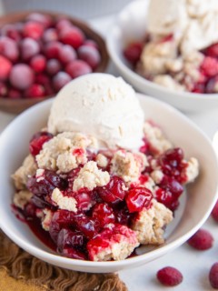 Two white bowls with fruit crip and vanilla ice cream on top.