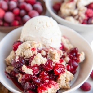 Two white bowls with fruit crip and vanilla ice cream on top.