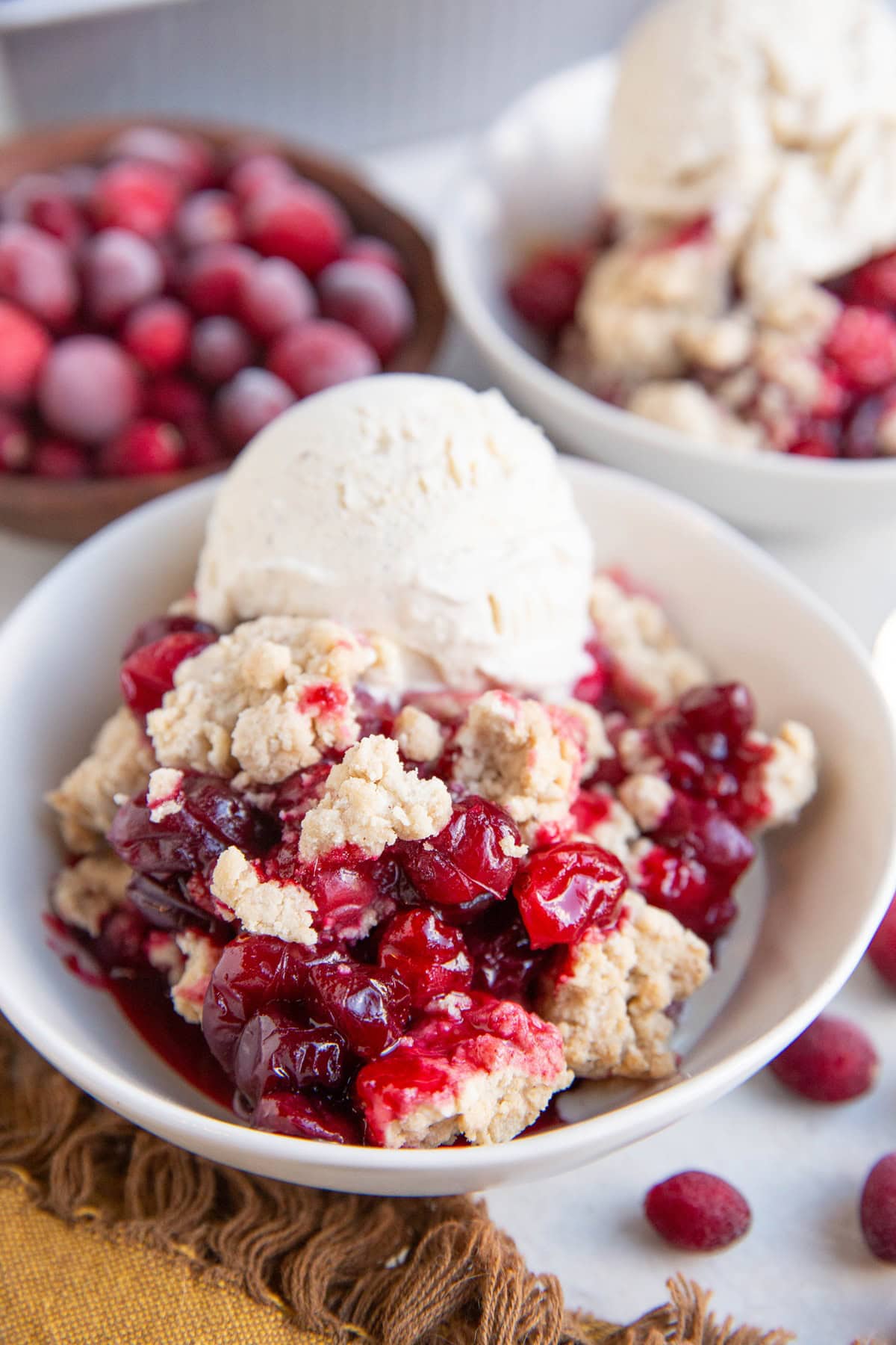 Two white bowls with fruit crip and vanilla ice cream on top.