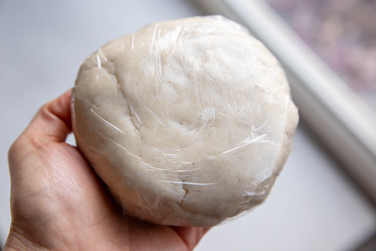 Disc of pie dough wrapped in plastic wrap.