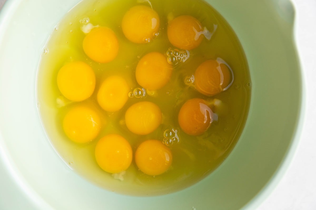 Twelve eggs in a mixing bowl, ready to be beaten.