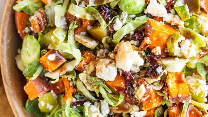 Big bowl of brussel sprout salad with sweet potato, blue cheese, dried cranberries, pears, and more.
