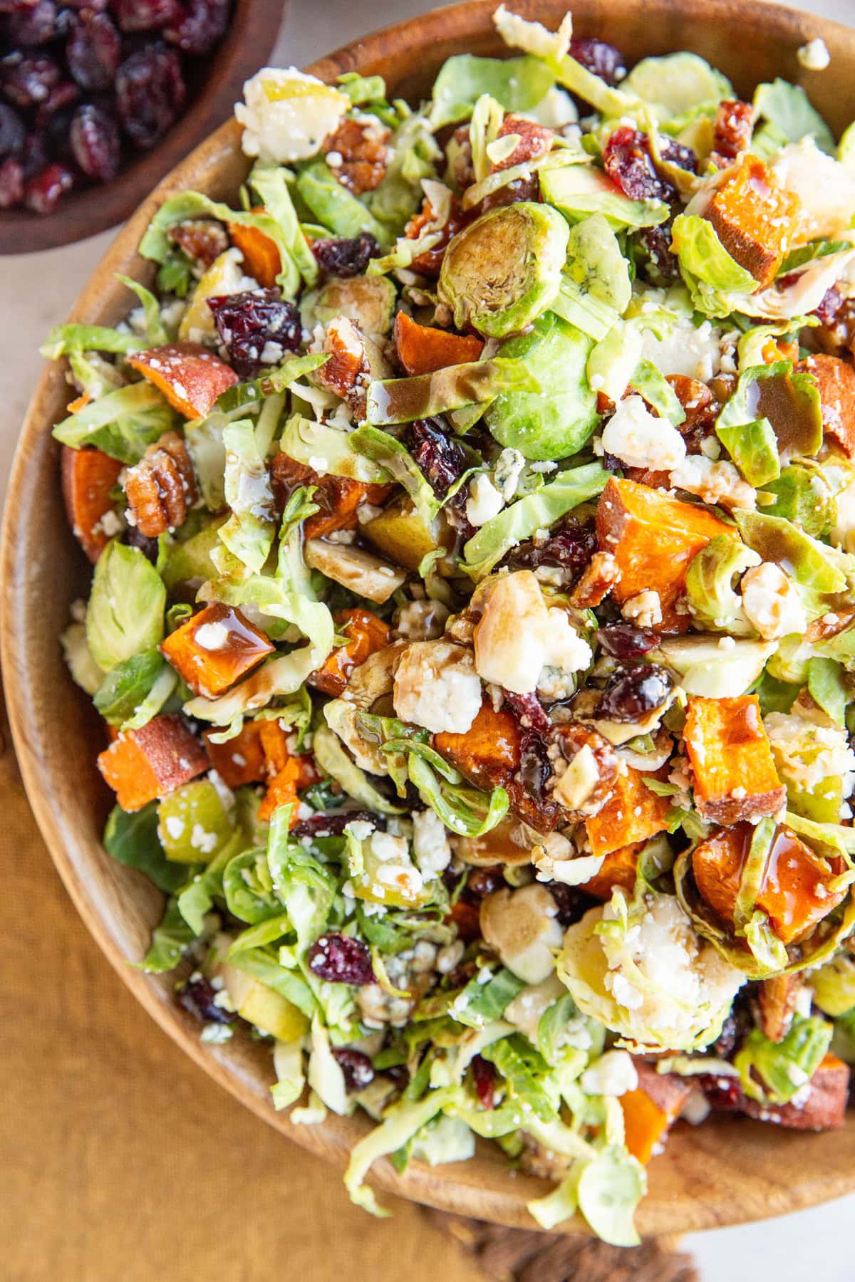 Big bowl of brussel sprout salad with sweet potato, blue cheese, dried cranberries, pears, and more.