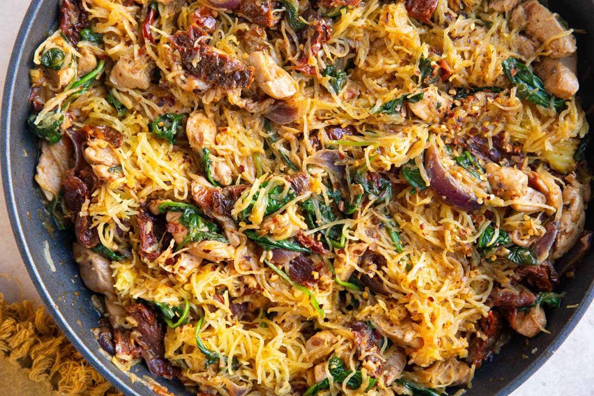 Sun-dried tomato spaghetti squash with chicken and spinach mixed together in a skillet, ready to eat.