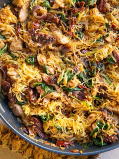 Sun-dried tomato spaghetti squash finished in a skillet, ready to serve and a napkin to the side.