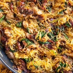 Sun-dried tomato spaghetti squash finished in a skillet, ready to serve and a napkin to the side.