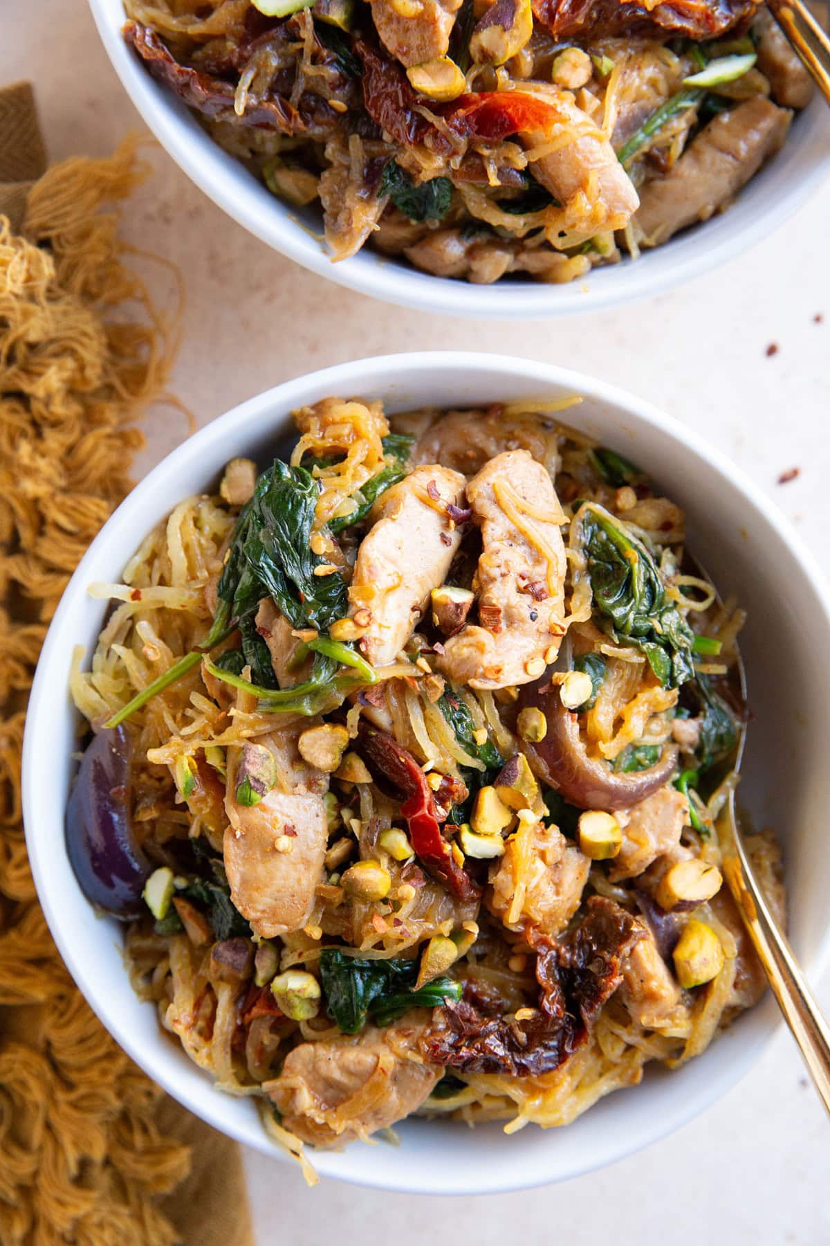 Spaghetti squash with chicken and sun-dried tomatoes in two white bowls, ready to eat.