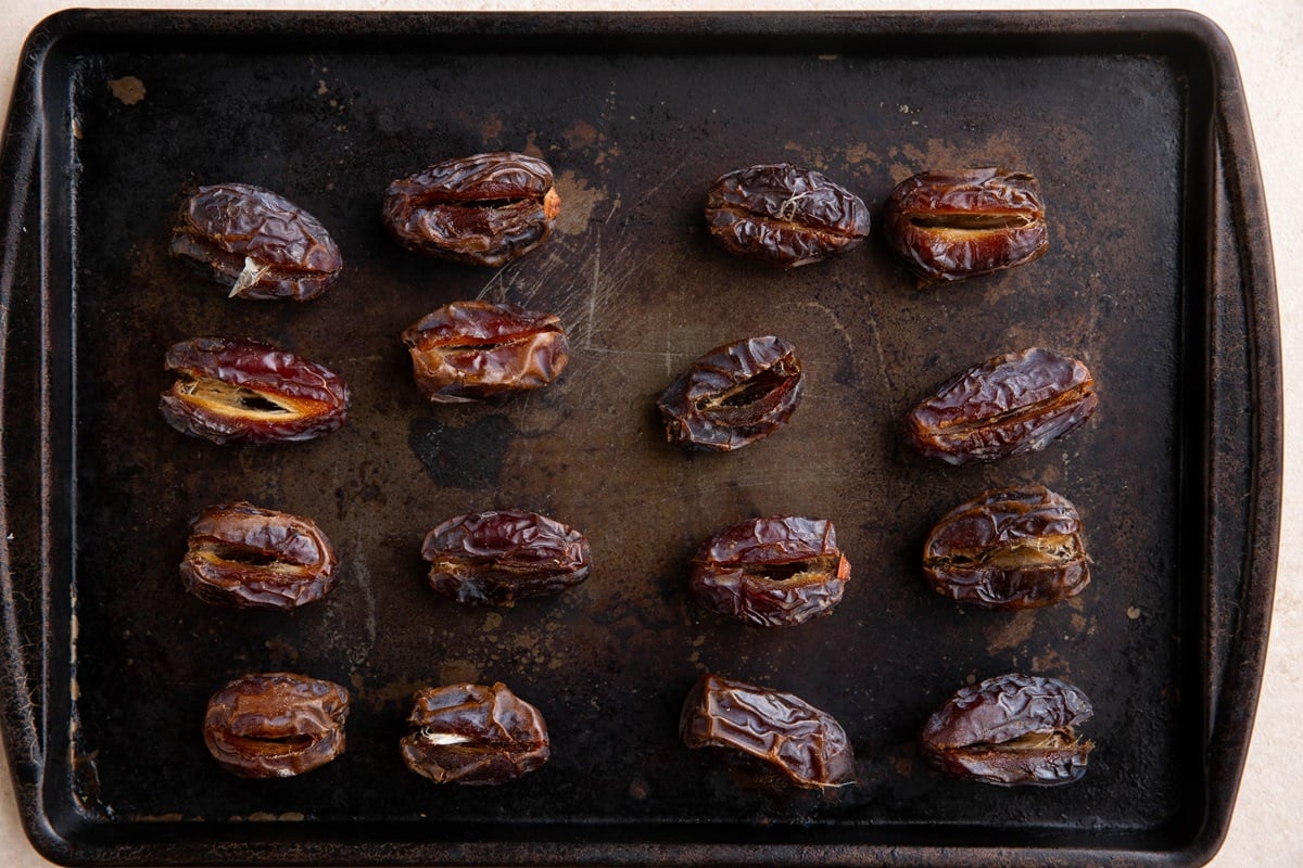 Pitted dates sitting on a baking sheet.