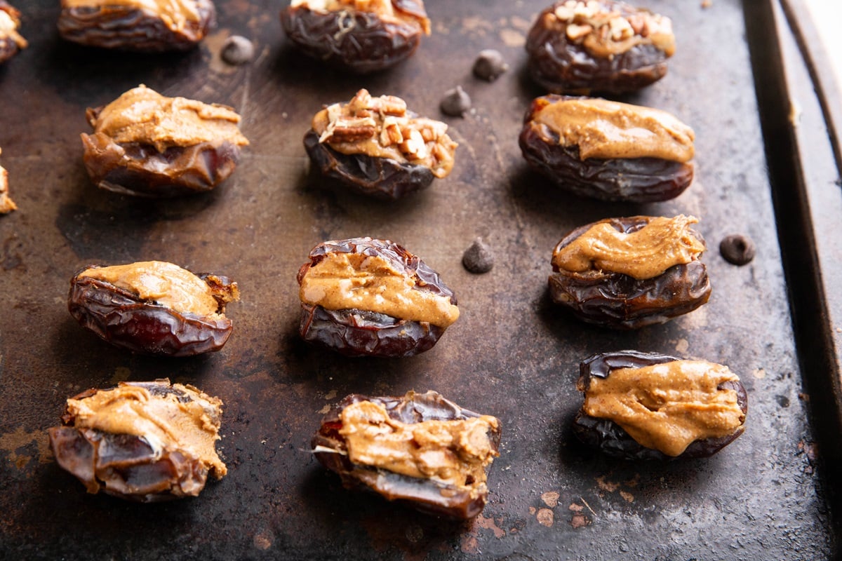 Dates stuffed with almond butter on a baking pan.
