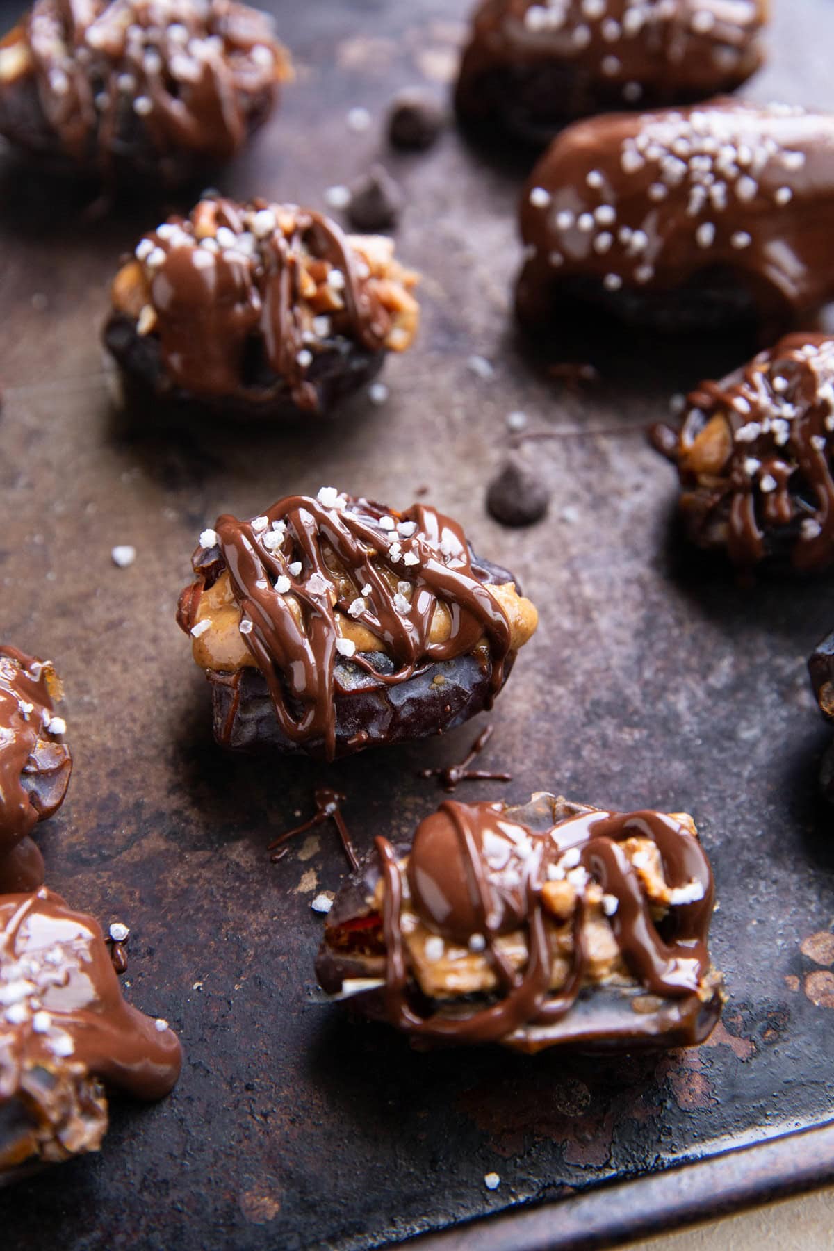 Baking sheet with dates stuffed with almond butter and drizzled with chocolate, ready to refrigerate.