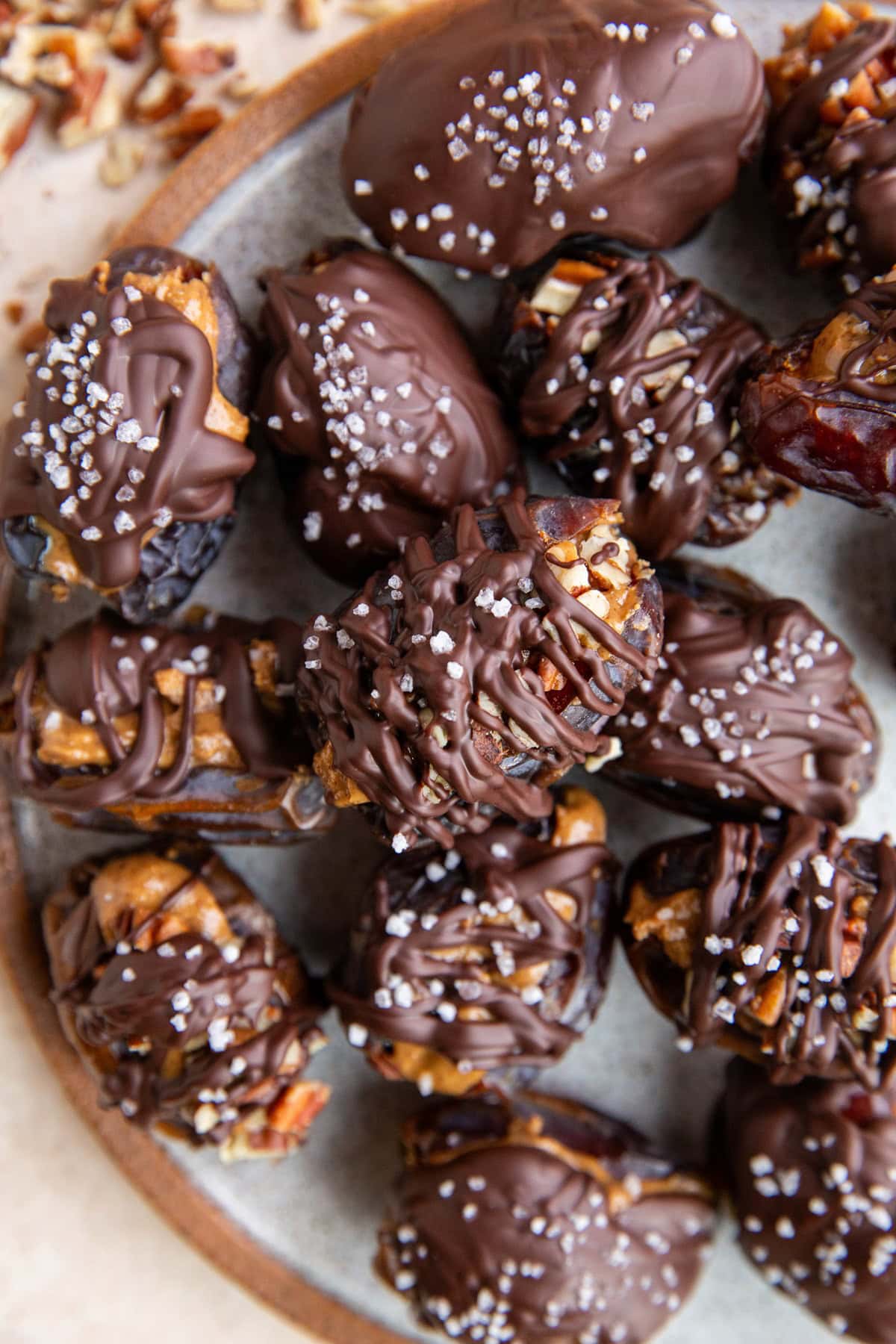 Plate of chocolate covered almond butter stuffed dates sprinkled with sea salt.