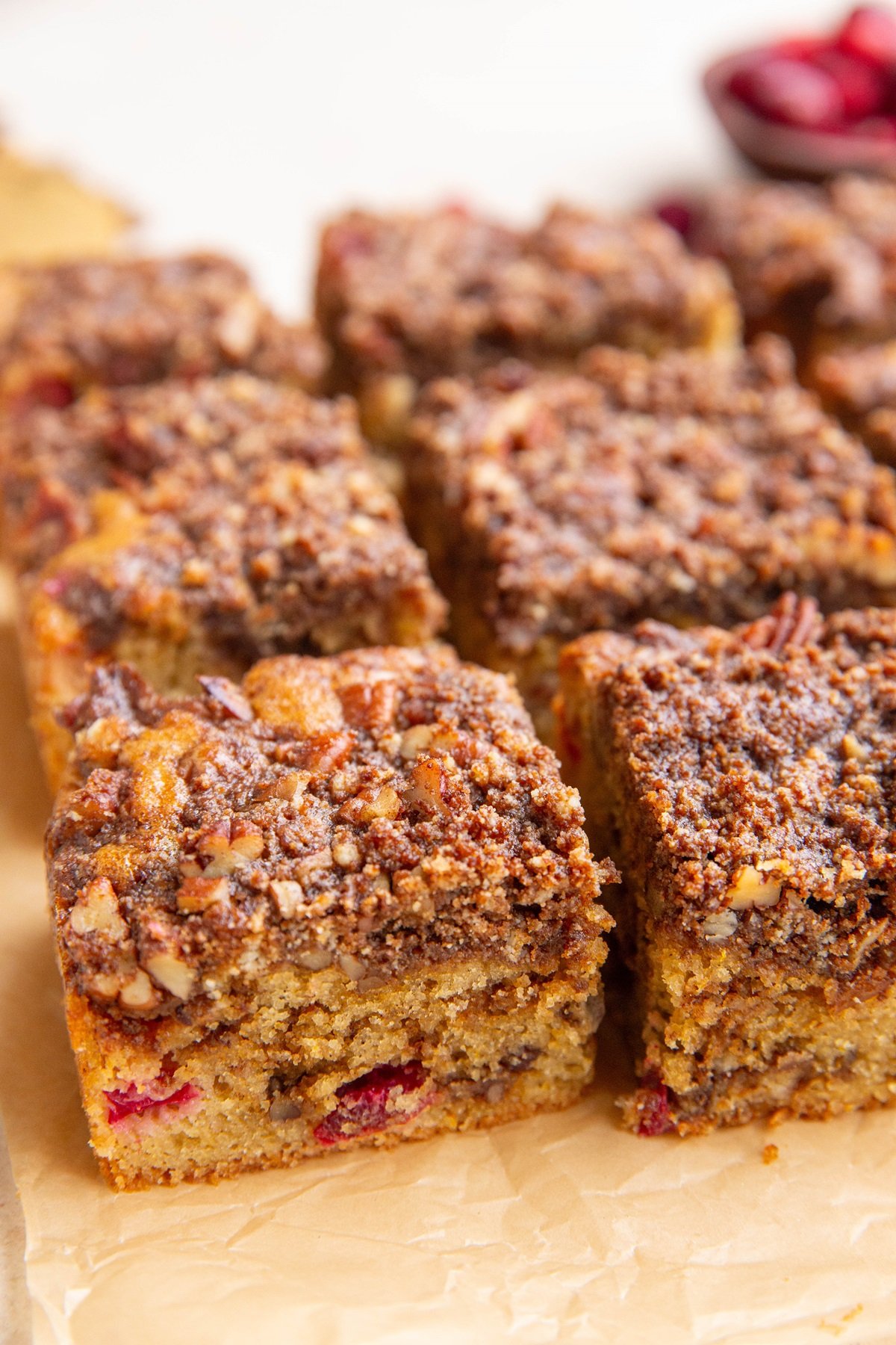 Grain-free cranberry orange coffee cake cut into slices on a sheet of parchment paper