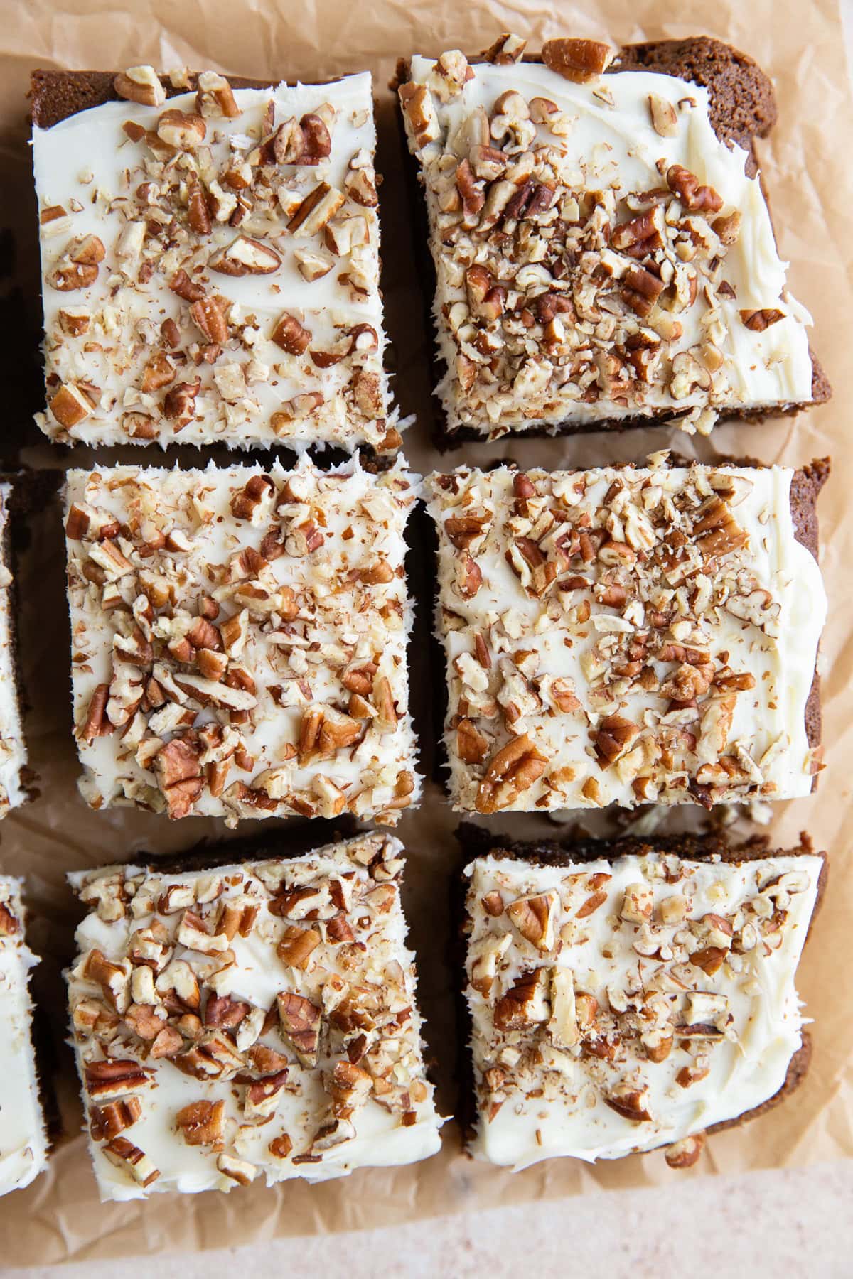 Gingerbread cake cut into slices on a sheet of parchment paper with cream cheese frosting on top.