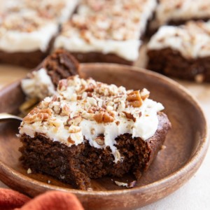 Slice of gingerbread cake on a wooden plate with a bite taken out.