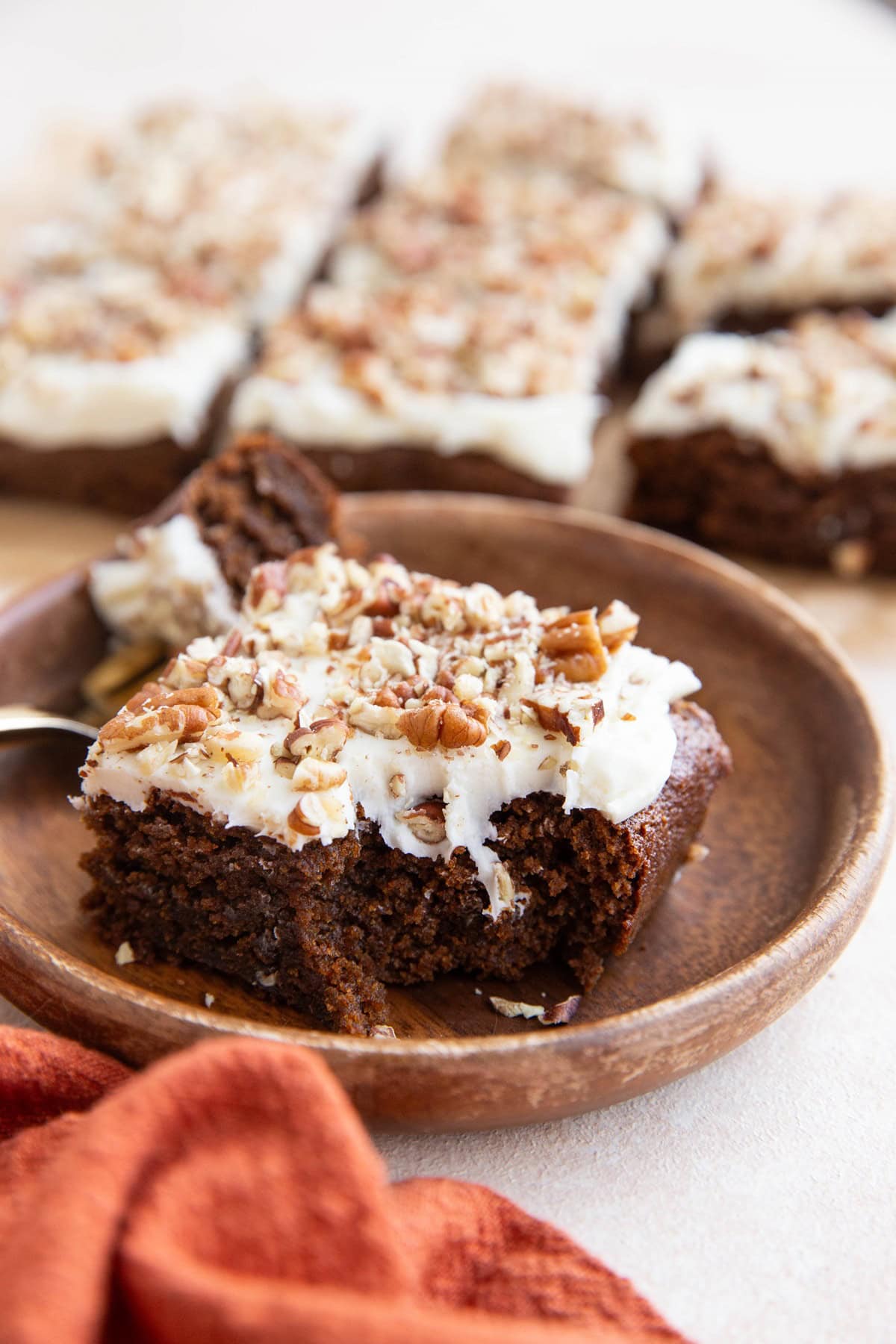 Slice of gingerbread cake on a wooden plate with a bite taken out.