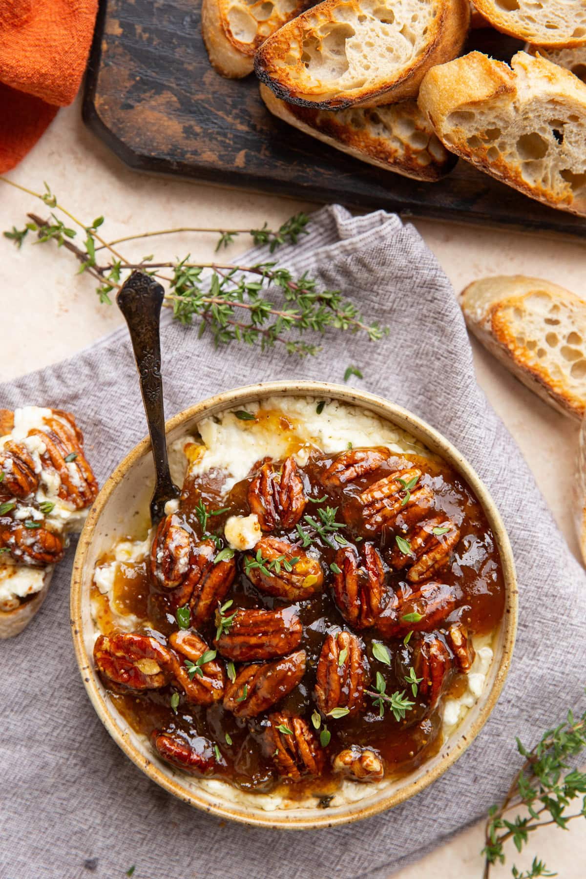 Bowl of baked feta dip with sliced crusty bread to the side.