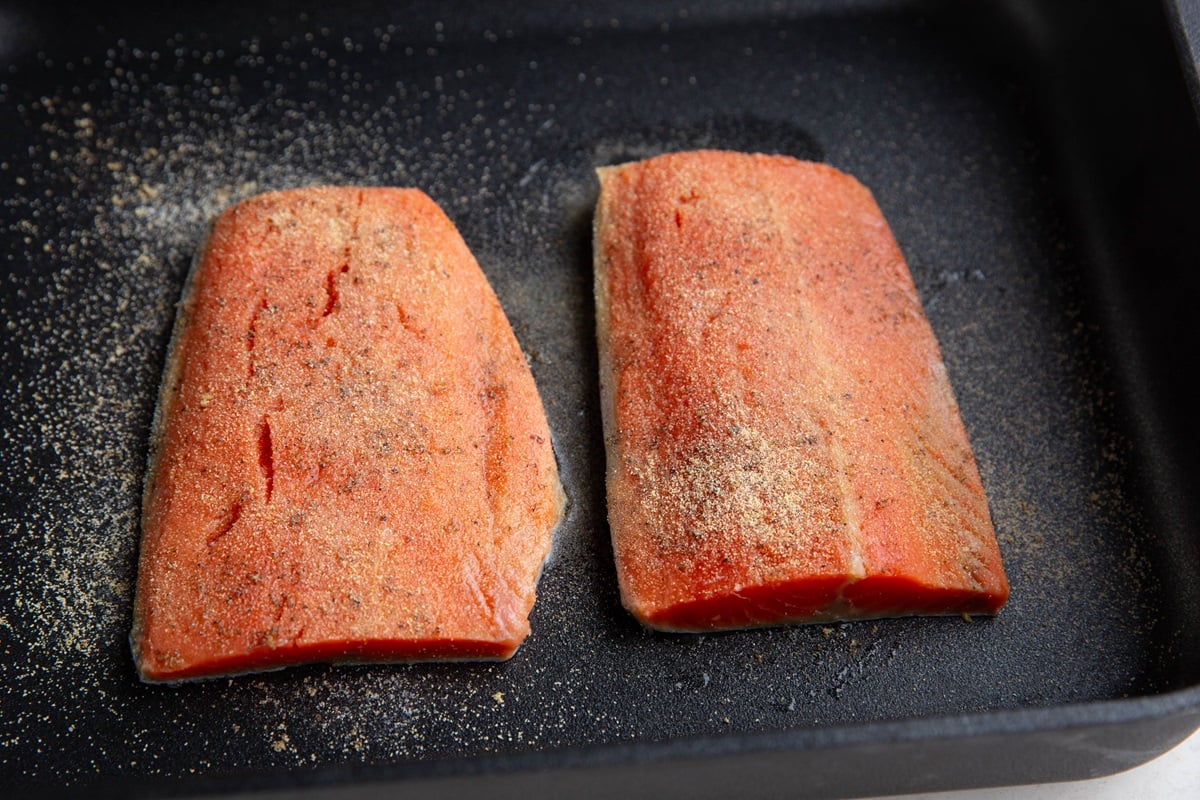 Sockeye salmon in a casserole dish drizzled with oil and sprinkled with seasoning, ready to go into the oven.
