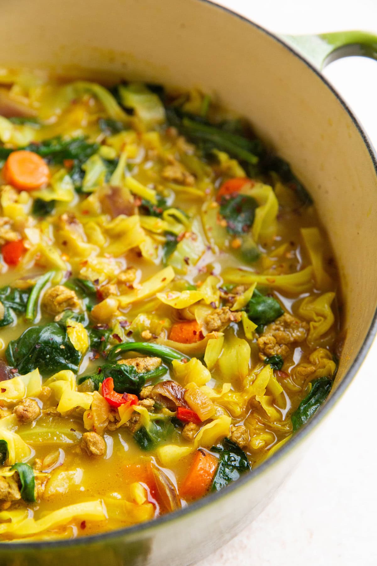 Ground turkey and cabbage soup with vegetables in a large pot.