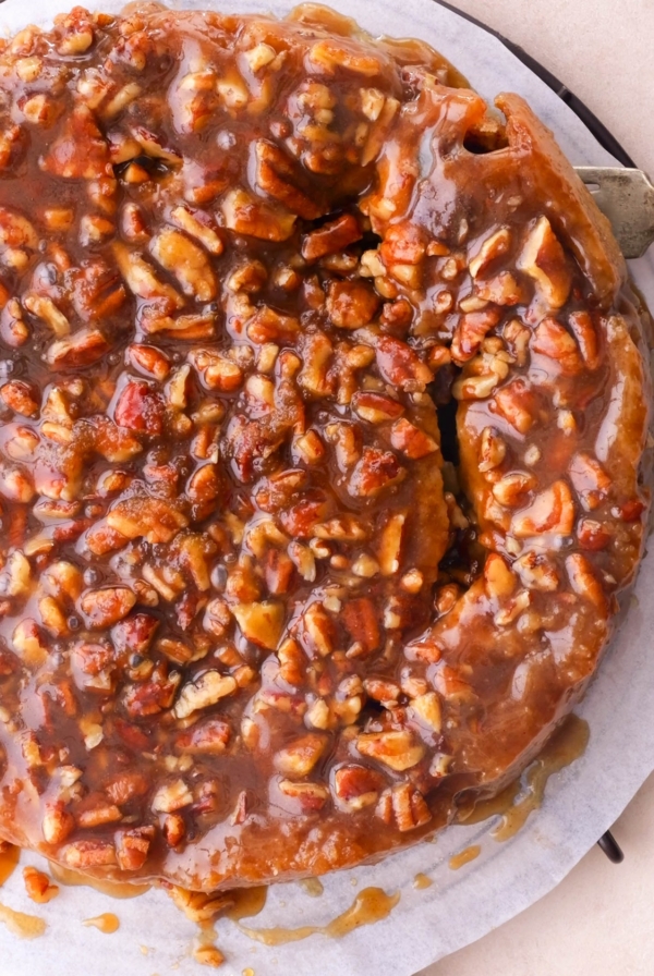 Full batch of pecan sticky buns on a serving plate with a fork taking one out.