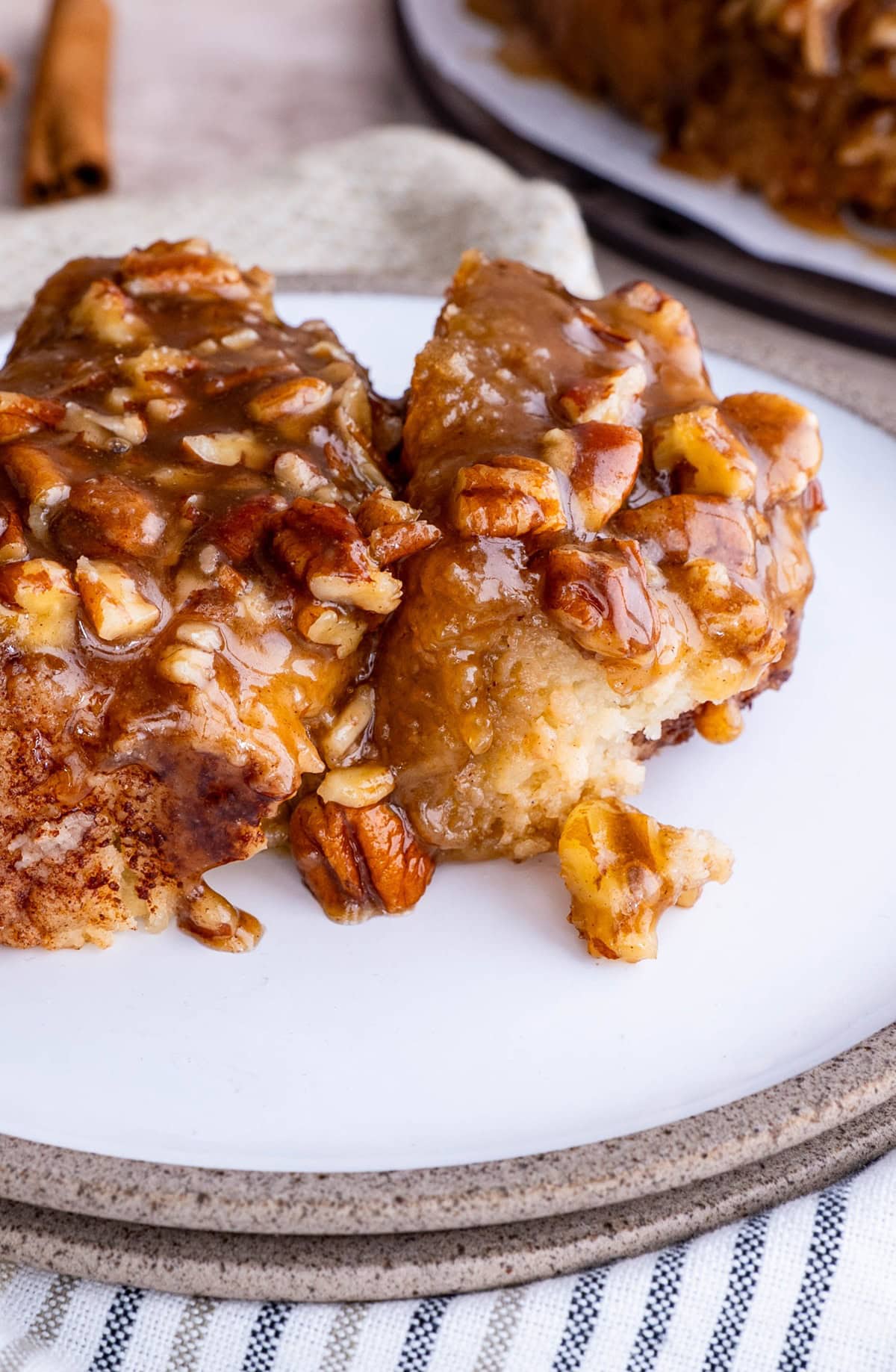 Pecan sticky bun on a white plate, ready to eat.