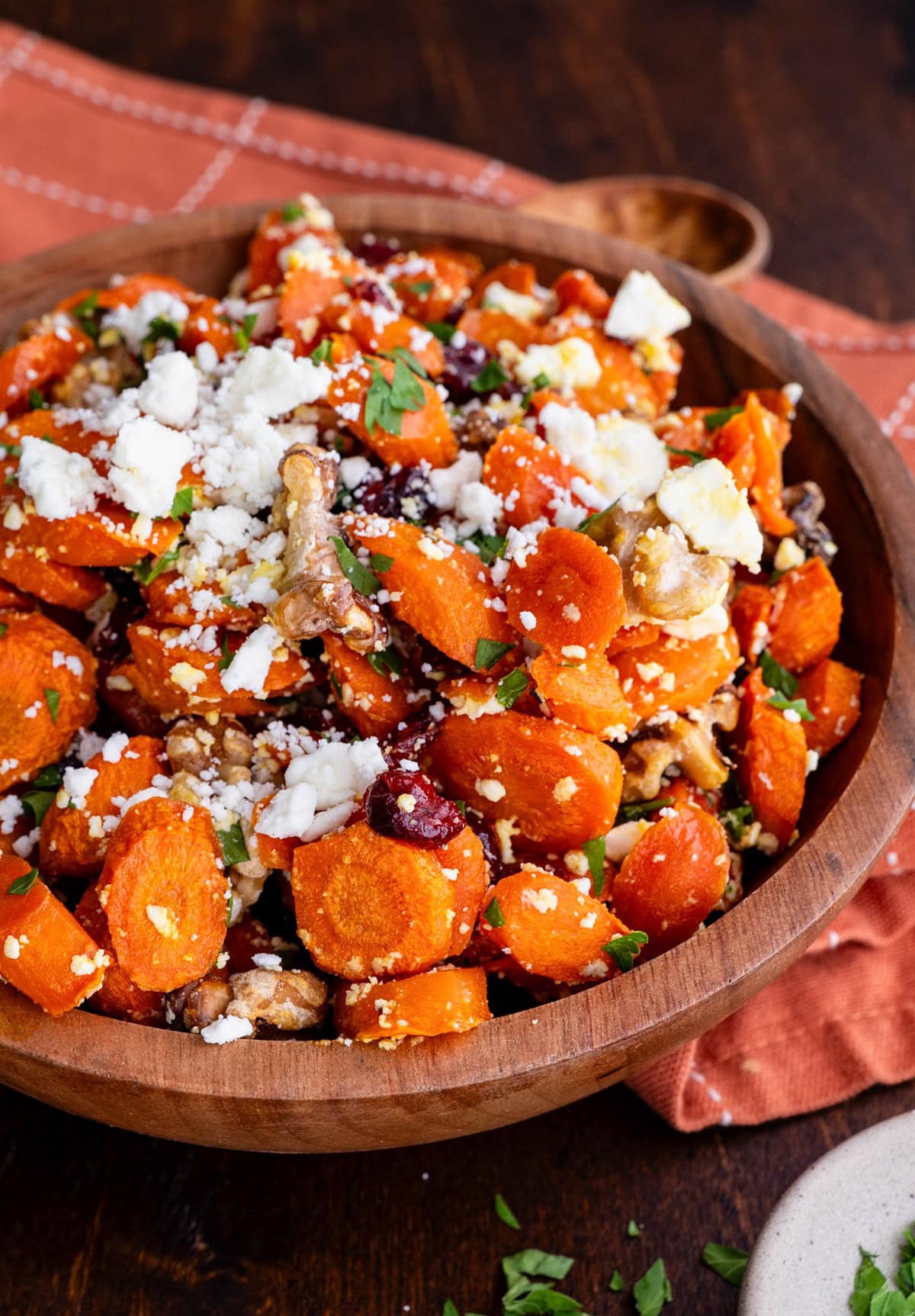 Wood bowl of roasted carrots with walnuts and feta cheese.