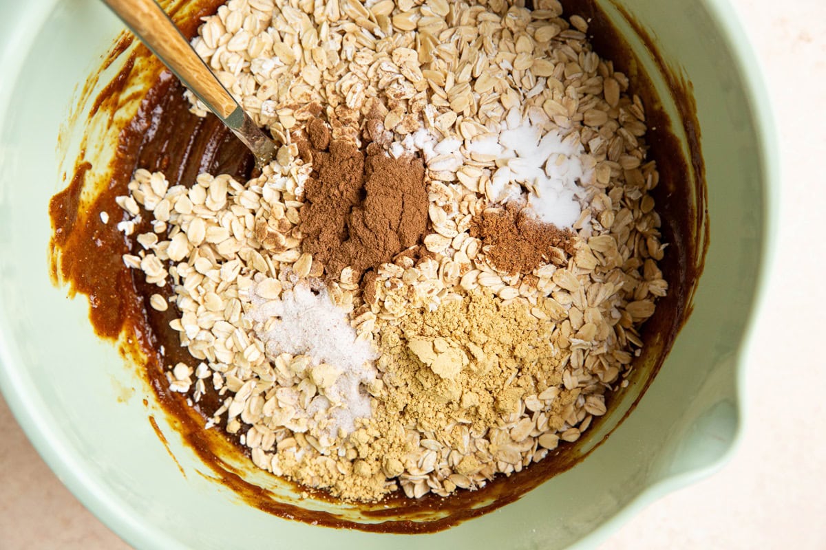 Dry ingredients on top of wet ingredients in a mixing bowl to make oatmeal ginger molasses cookies.