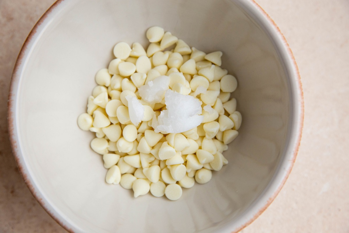 White chocolate chips in a bowl with coconut oil, ready to be microwaved.