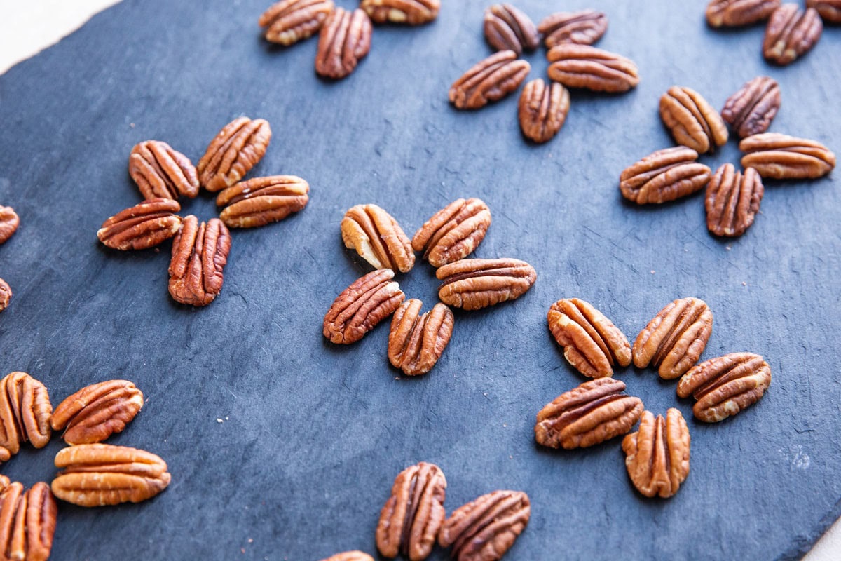 Pecan formations on a cutting board to make pecan turtles.