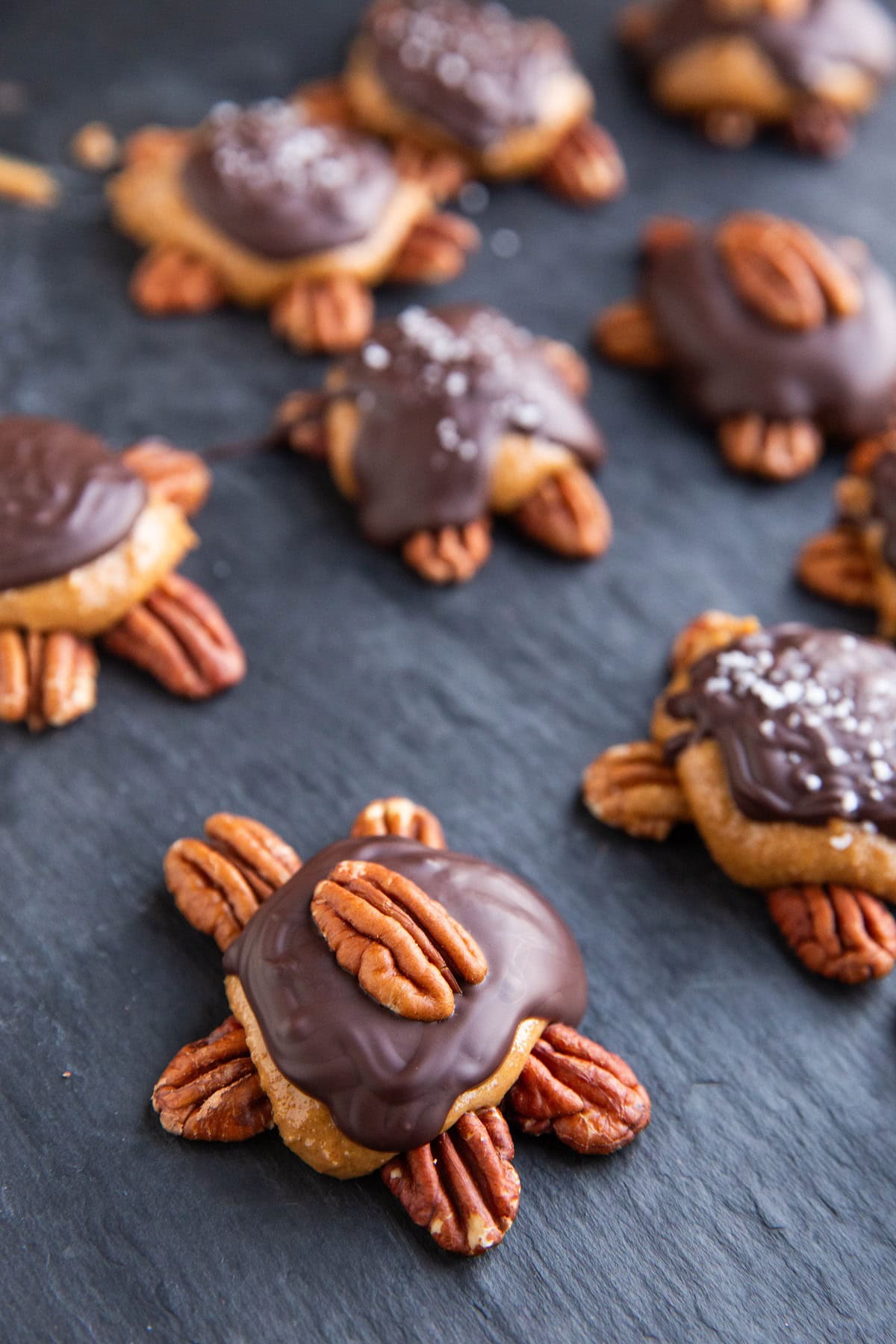 Pecan turtles on a black cutting board.