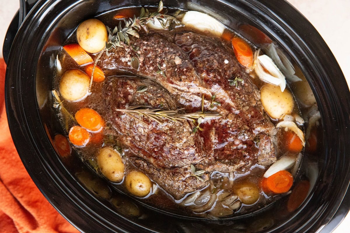 Crock pot full of pot roast and vegetables, ready to serve.