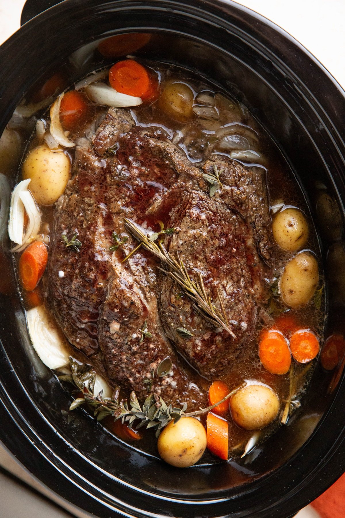 Slow cooker with beef roast and vegetables, ready to serve.