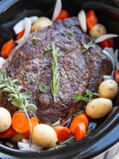 Crock pot with meat and vegetables inside, ready to slow cook.